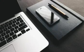 A laptop, pen, and smartphone arranged neatly on a table, showcasing modern techinsiderz.com gadgets and productivity tools.