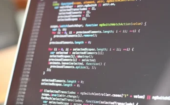 A laptop displaying a screen filled with code, featuring the nzbgeek logo prominently in the corner.