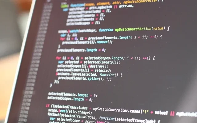 A laptop displaying a screen filled with code, featuring the nzbgeek logo prominently in the corner.