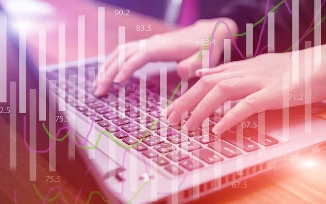 Close-up of hands on a laptop keyboard, analyzing stock market graphs for GomyFinance invest insights.