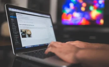 A person types on a laptop, focused on a tech feedbuzzard displaying various news and updates.