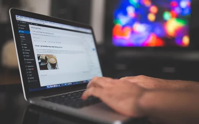 A person types on a laptop, focused on a tech feedbuzzard displaying various news and updates.